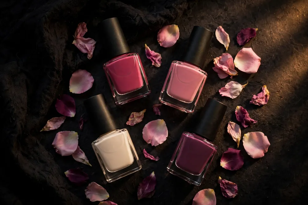 Nail lacquer bottles in pink, rose and plum on a dark surface